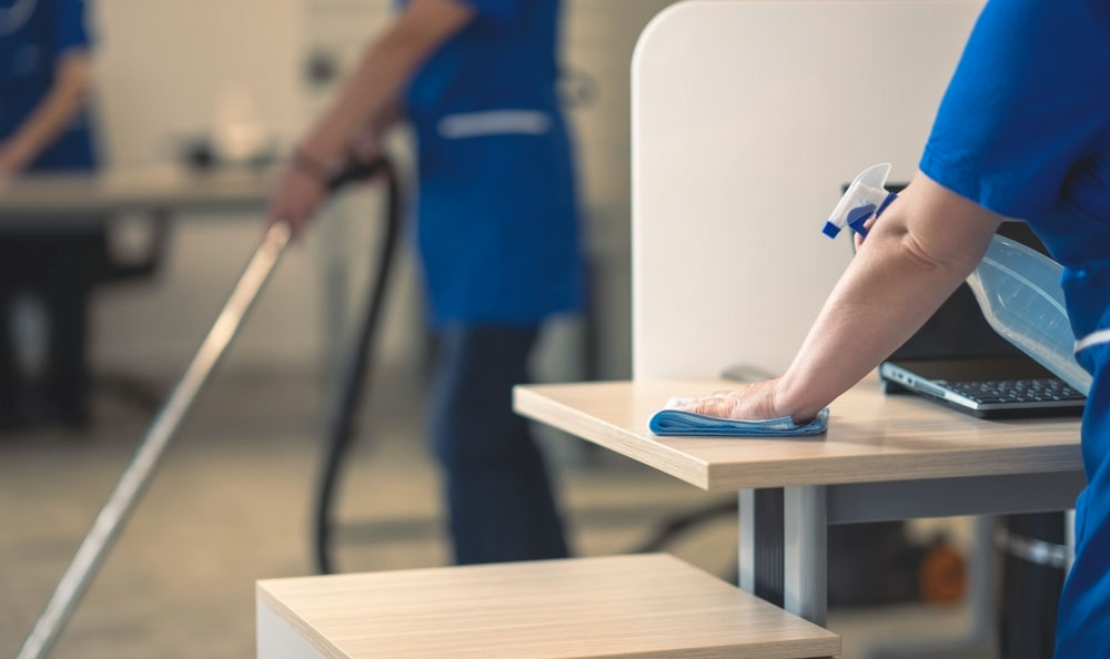 How Often Should an Office Be Cleaned? Person cleaning desk