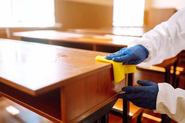 School Cleaning Services person cleaning a school desk