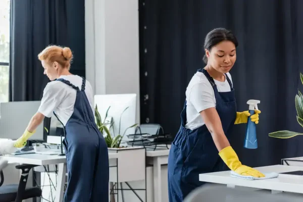 two women cleaning office desks
