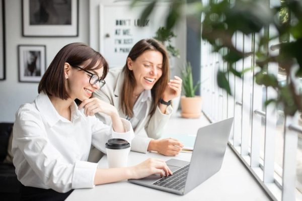 two women laughing at their desk